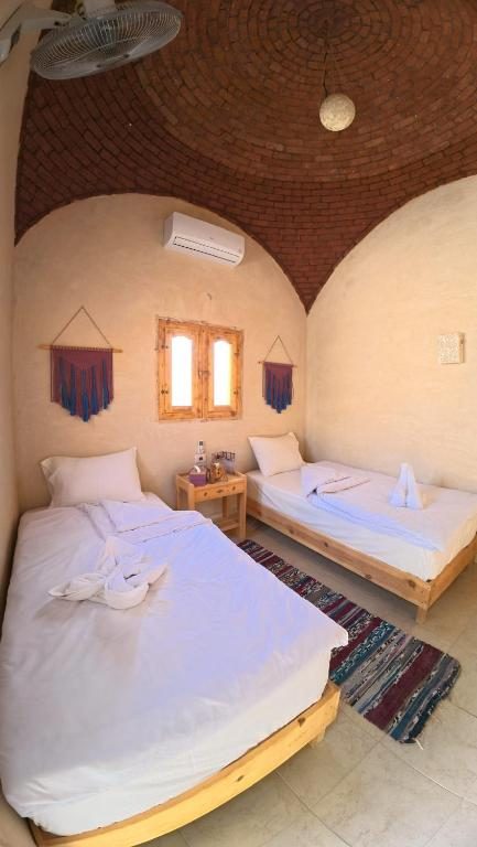 Twin room beneath a domed brick ceiling with woven wall hangings