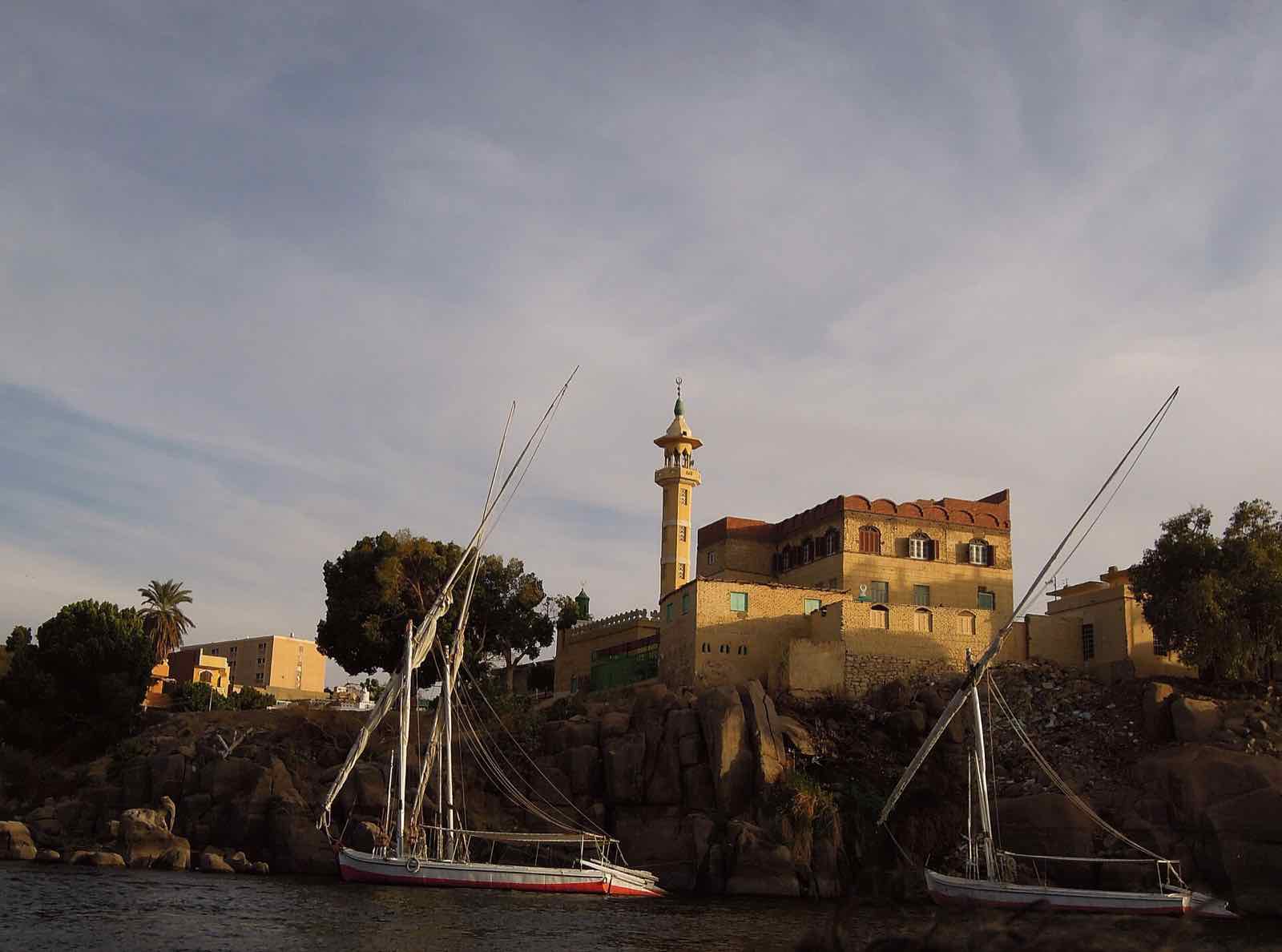 Feluccas moored below a mosque on the Nile at Aswan in evening light
