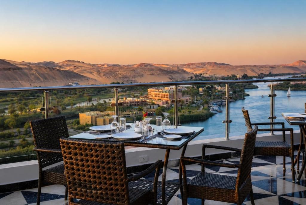 Rooftop restaurant tables overlooking the Nile and desert hills at sunset