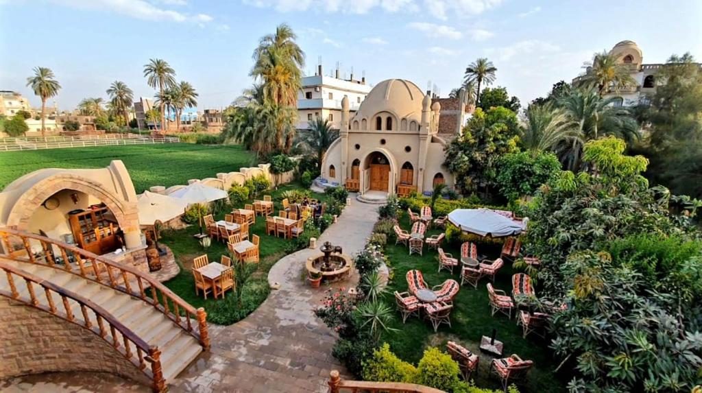 Domed mud-brick buildings and a garden with outdoor seating beside green fields