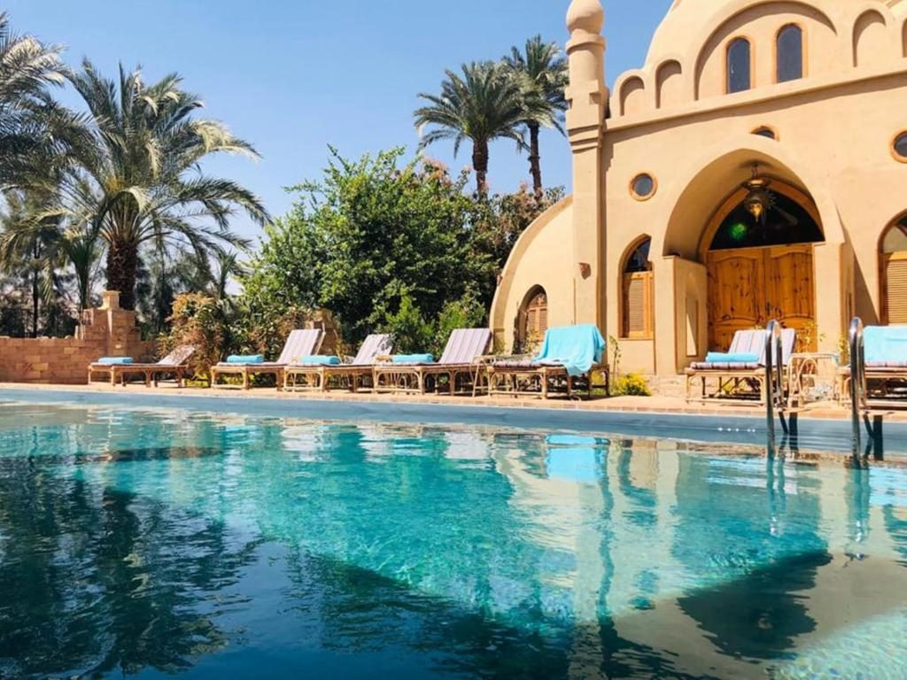 Pool with sun loungers beneath palms and a domed building