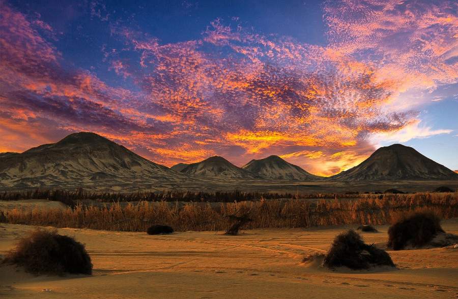 Volcanic hills of the Black Desert under a fiery sunset sky